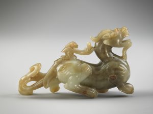 carved jade chimera with a small figure riding on its back